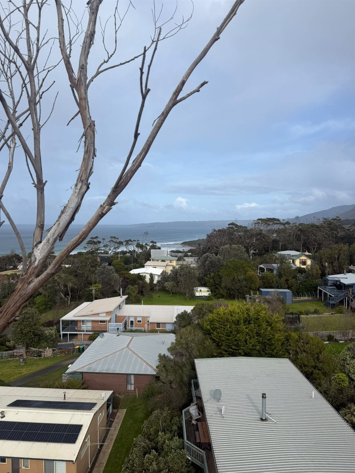 Elevated view over Skenes Creek rooftops out to the ocean and headland